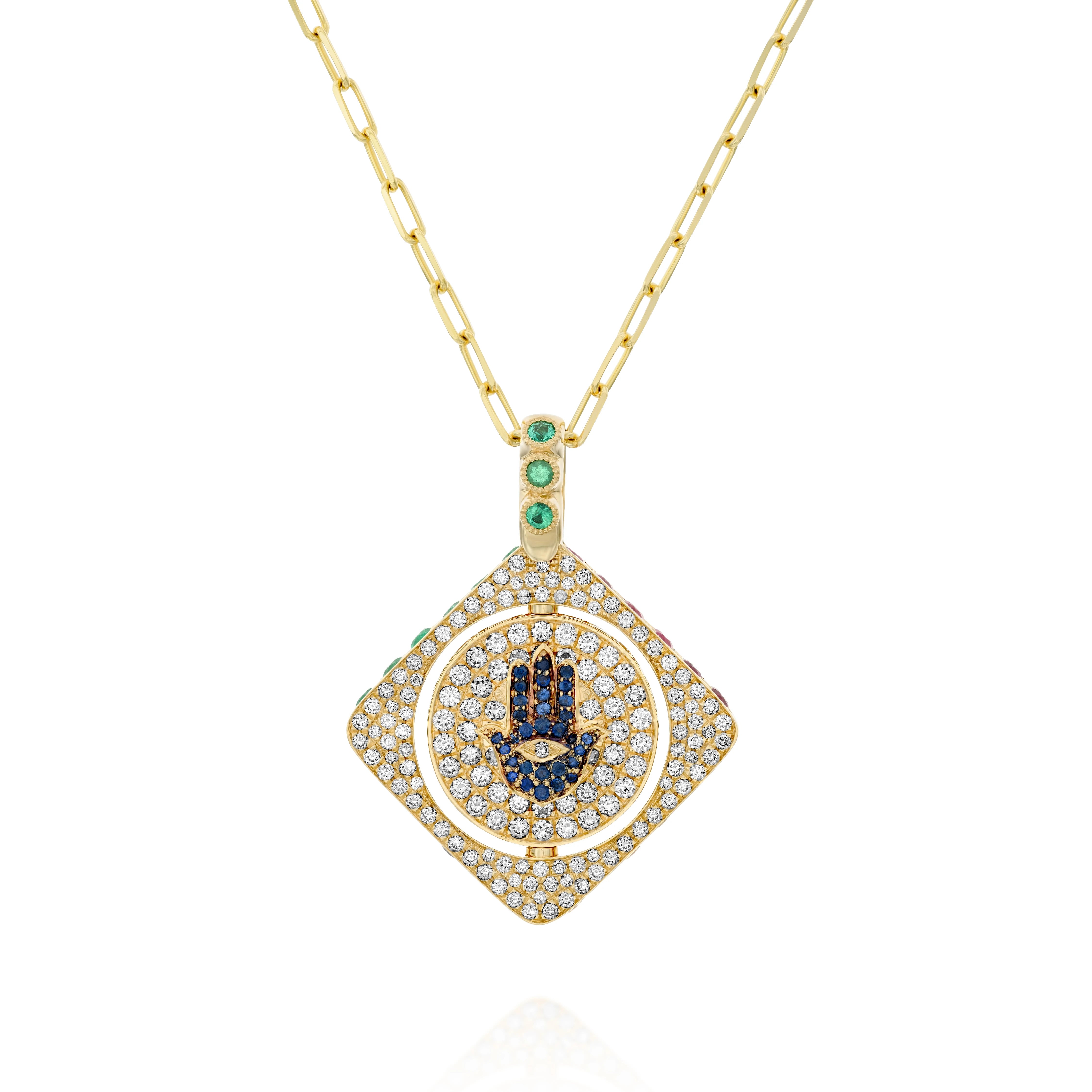 18k gold double-sided spinning pendant featuring a circle within a square design with a protective Hamsa motif. Set with diamonds, sapphires, rubies, and emeralds, this unique piece transforms its appearance with each turn, offering multiple looks in one stunning jewel. The pendant combines traditional protective symbolism with modern luxury design.