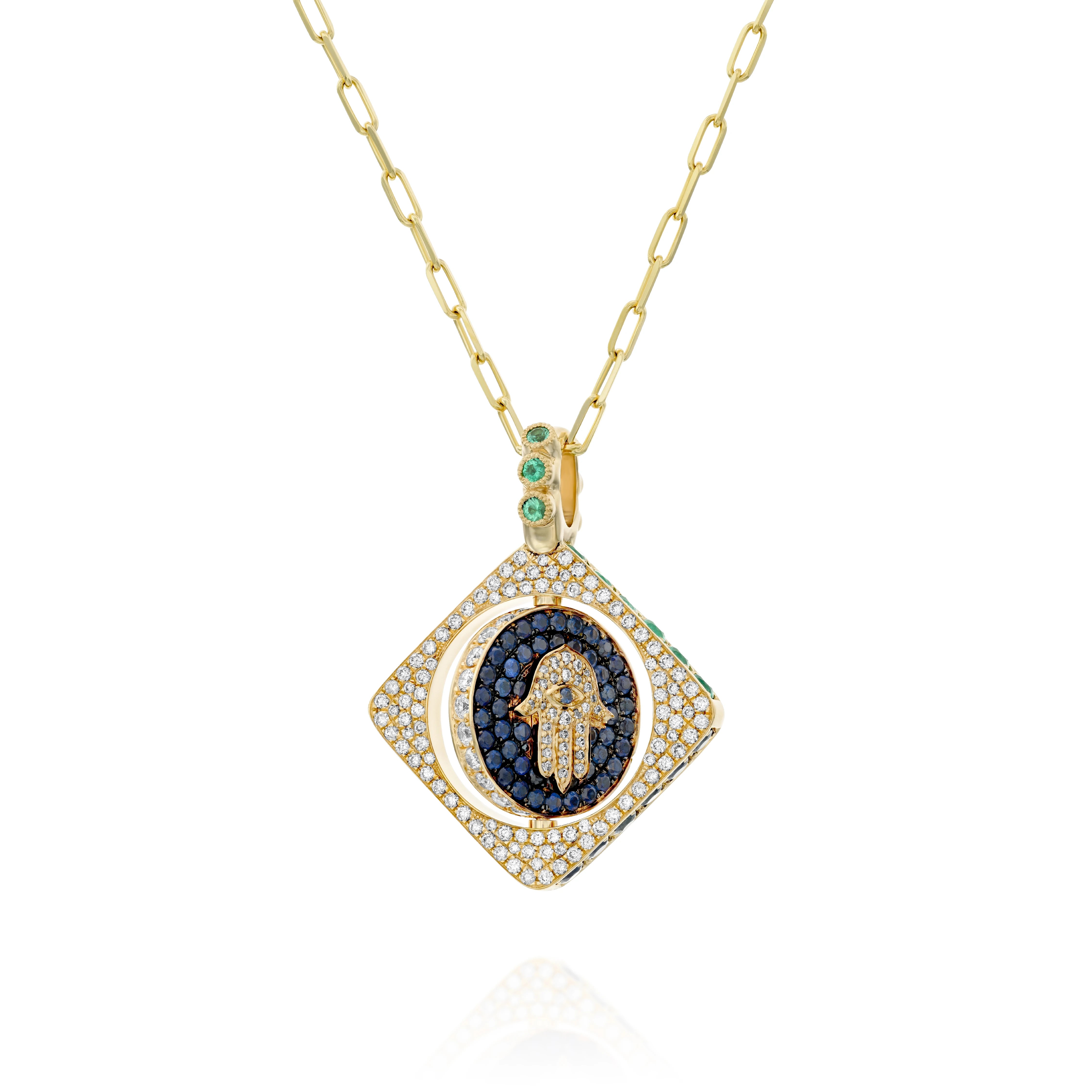 18k gold double-sided spinning pendant featuring a circle within a square design with a protective Hamsa motif. Set with diamonds, sapphires, rubies, and emeralds, this unique piece transforms its appearance with each turn, offering multiple looks in one stunning jewel. The pendant combines traditional protective symbolism with modern luxury design.